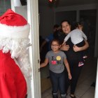 Santa Claus, a volunteer with "Presents on Patrol," surprises Maria Herrera, baby Daisy Mercado and Kevin Mercado.